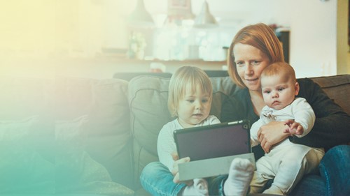 A parent and two children looking at a tablet together at home